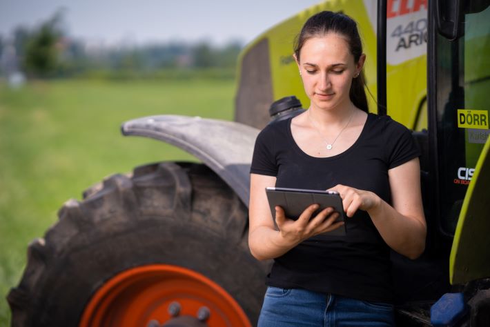 Frau mit Tablet vor Traktor